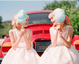 Duas meninas com algodão doce em frente a um carro vermelho