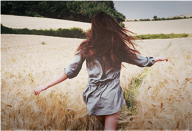 menina corre diante de uma plantação de trigo